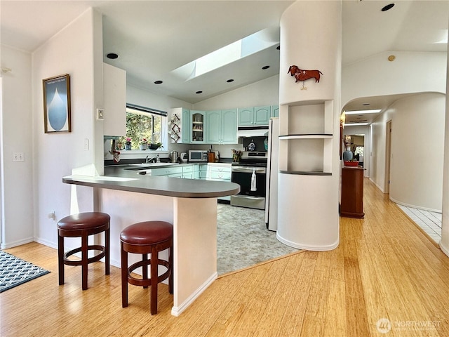 10 Davenhill Ln, Sequim, WA 98382 - kitchen featuring appliances with stainless steel finishes, a skylight, a peninsula, vaulted ceiling, and light wood-style flooring
