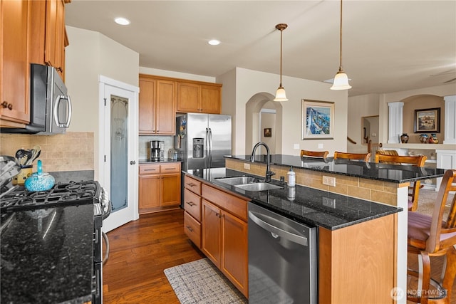 5539 Charlotte Ave SE, Auburn, WA 98092 - kitchen featuring appliances with stainless steel finishes, an island with sink, decorative backsplash, arched walkways, and recessed lighting