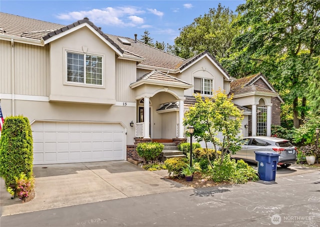 8221 53rd Ave W Unit 15C, Mukilteo, WA 98275 - view of front of property featuring a tile roof, brick siding, a garage, concrete driveway, and stucco siding
