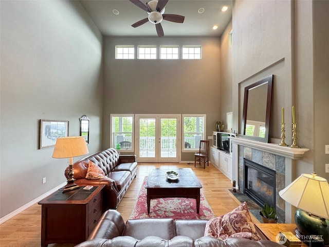453 Louella Heights Dr, Sequim, WA 98382 - living area featuring a towering ceiling, a ceiling fan, a tiled fireplace, and light wood-style flooring