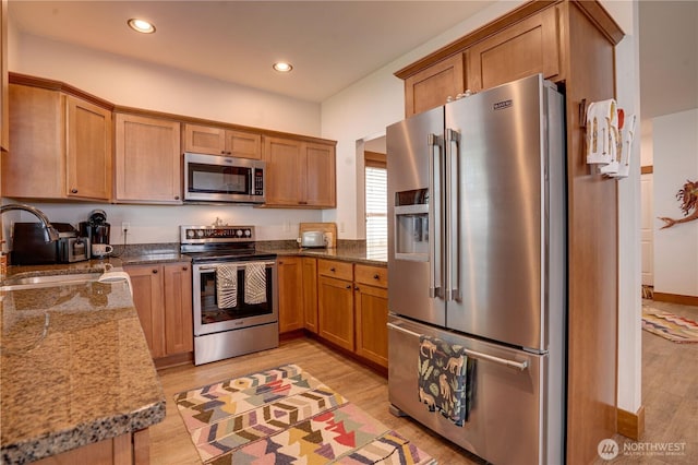 2452 NW Columbia Ave Unit 34, East Wenatchee, WA 98802 - kitchen with appliances with stainless steel finishes, light wood-style flooring, dark stone counters, brown cabinets, and recessed lighting
