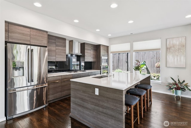 12914 SE 213th, Kent, WA 98031 - kitchen featuring appliances with stainless steel finishes, wall chimney range hood, modern cabinets, a breakfast bar, and a center island with sink