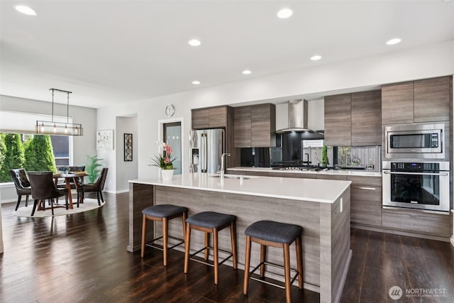 12914 SE 213th, Kent, WA 98031 - kitchen with appliances with stainless steel finishes, wall chimney exhaust hood, a kitchen bar, modern cabinets, and recessed lighting
