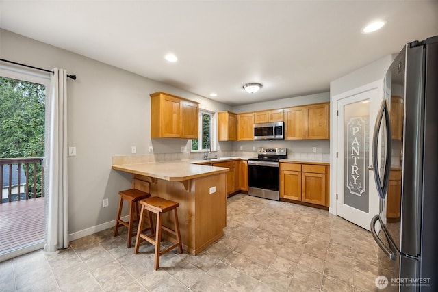 17712 E Clear Lake Blvd SE, Yelm, WA 98597 - kitchen with stainless steel appliances, a peninsula, light countertops, recessed lighting, and a kitchen bar