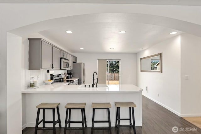 20008 99th Ave E, Graham, WA 98338 - kitchen featuring appliances with stainless steel finishes, a kitchen breakfast bar, light countertops, dark wood-style floors, and a peninsula