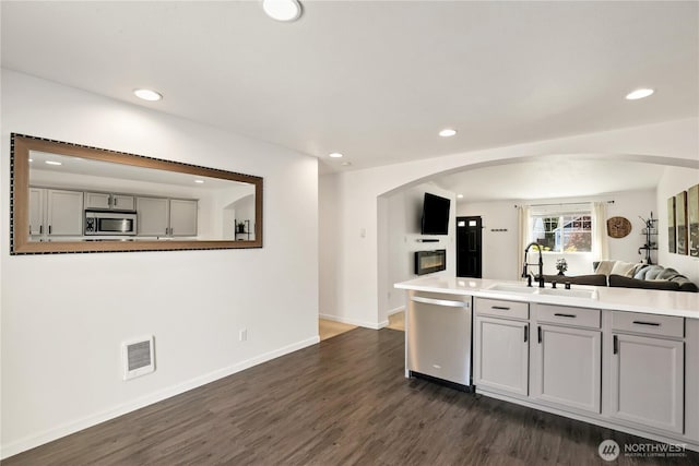 20008 99th Ave E, Graham, WA 98338 - kitchen featuring appliances with stainless steel finishes, arched walkways, open floor plan, gray cabinetry, and dark wood-style flooring