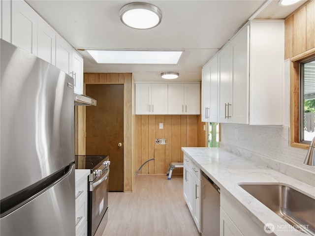 9128 184th Ave NE, Granite Falls, WA 98252 - kitchen with appliances with stainless steel finishes, light wood-type flooring, white cabinets, light stone counters, and wood walls