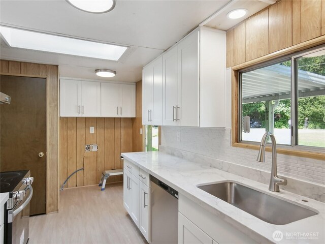 9128 184th Ave NE, Granite Falls, WA 98252 - kitchen with stainless steel appliances, white cabinetry, light wood-style floors, tasteful backsplash, and wood walls