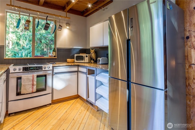 251 Saddle Dr, Port Townsend, WA 98368 - kitchen featuring appliances with stainless steel finishes, white cabinets, light wood-style floors, light stone counters, and a wooden ceiling with exposed beams