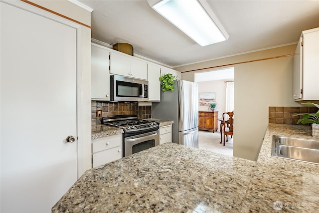1021 Garden Dr, Lynden, WA 98264 - kitchen featuring appliances with stainless steel finishes, backsplash, white cabinetry, crown molding, and a peninsula