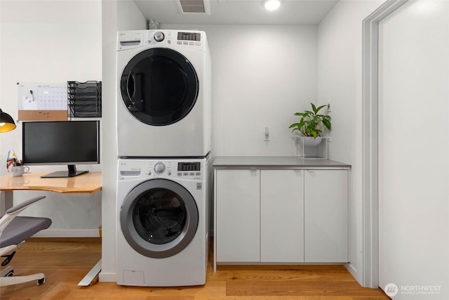 866 NE 96th St, Seattle, WA 98115 - laundry area featuring stacked washing machine and dryer, cabinet space, light wood-style flooring, and a desk