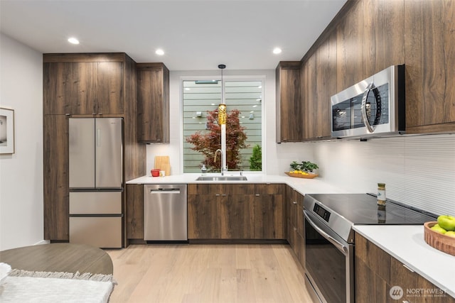 2665 51st Ave SW, Seattle, WA 98116 - kitchen featuring stainless steel appliances, light wood finished floors, light countertops, dark brown cabinets, and recessed lighting