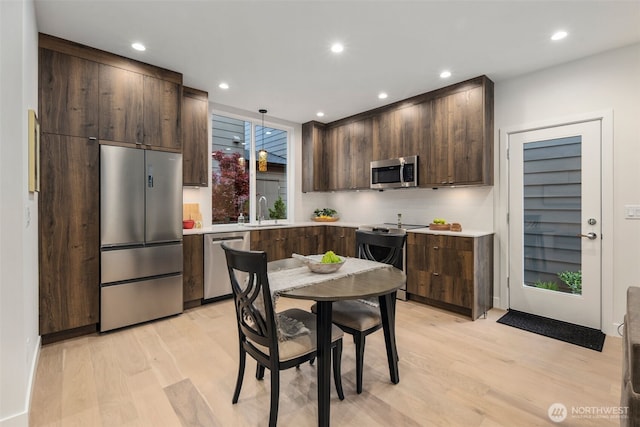 2665 51st Ave SW, Seattle, WA 98116 - kitchen featuring stainless steel appliances, dark brown cabinetry, light wood-type flooring, light countertops, and recessed lighting