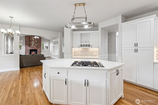 14808 172nd St E, Orting, WA 98360 - kitchen with stainless steel gas cooktop, white cabinets, light wood-type flooring, and a center island