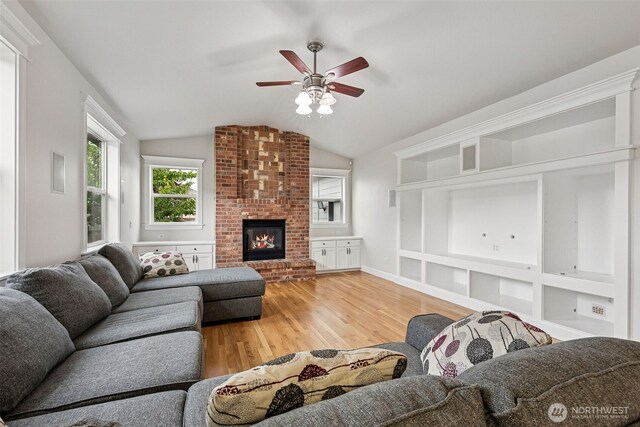 14808 172nd St E, Orting, WA 98360 - living area featuring light wood finished floors, lofted ceiling, a ceiling fan, a brick fireplace, and built in shelves