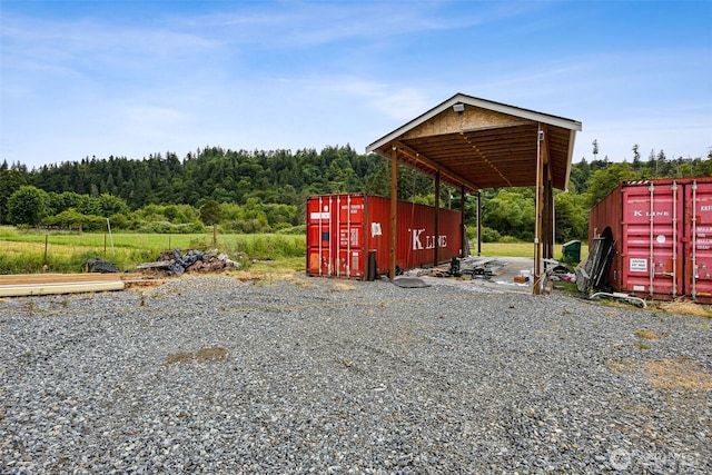 14808 172nd St E, Orting, WA 98360 - view of parking featuring a detached carport and a wooded view