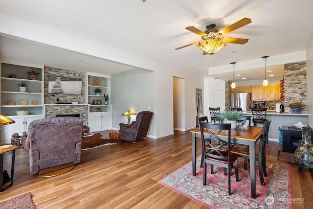 418 17th St SE Unit 9D, Auburn, WA 98002 - dining room with a ceiling fan, wood finished floors, a large fireplace, and built in shelves