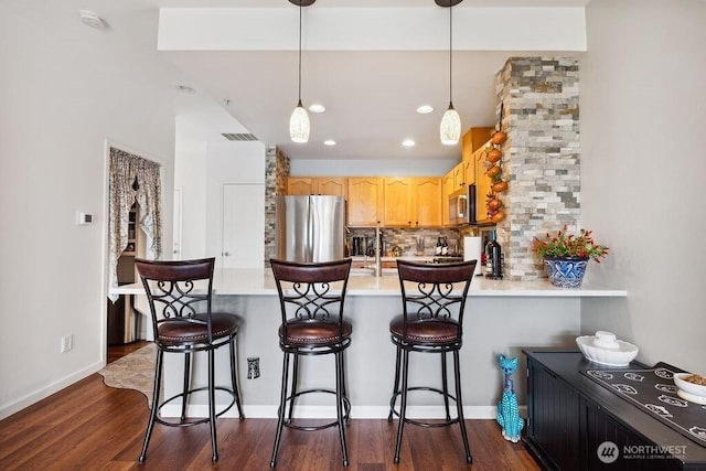418 17th St SE Unit 9D, Auburn, WA 98002 - kitchen featuring appliances with stainless steel finishes, a peninsula, light countertops, tasteful backsplash, and dark wood-type flooring