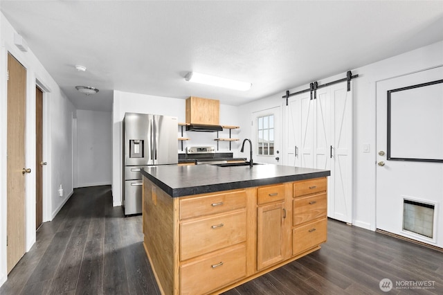 307 Brown St SE, Orting, WA 98360 - kitchen with stainless steel appliances, dark countertops, range hood, dark wood-style flooring, and a center island with sink