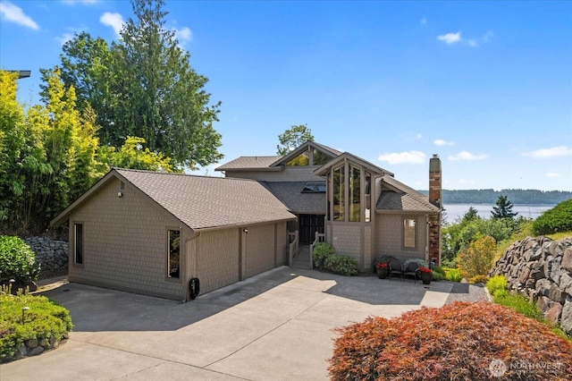 10300 64th Pl W, Mukilteo, WA 98275 - view of front of home with a chimney, an attached garage, a shingled roof, a water view, and concrete driveway