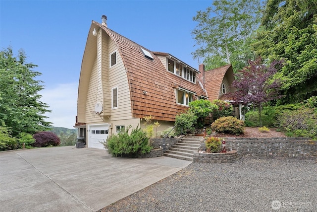 1508 Bloomhardt Rd, Raymond, WA 98577 - view of property exterior featuring a gambrel roof, stairs, a garage, driveway, and a chimney