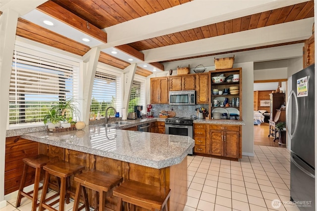 1508 Bloomhardt Rd, Raymond, WA 98577 - kitchen featuring appliances with stainless steel finishes, a peninsula, brown cabinetry, decorative backsplash, and light tile patterned flooring