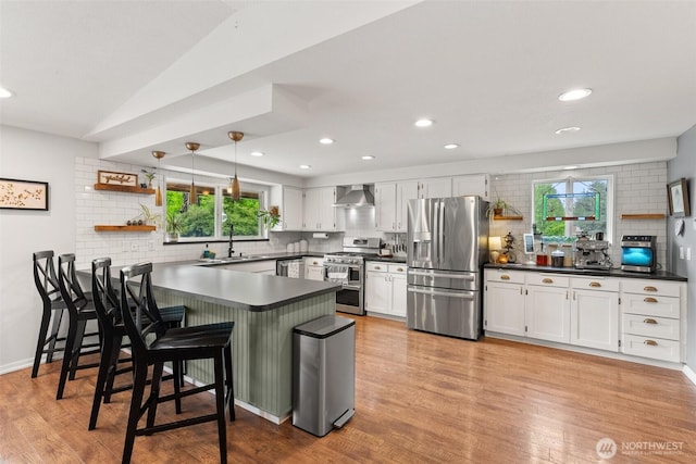 755 Elm St, Raymond, WA 98577 - kitchen with appliances with stainless steel finishes, a peninsula, decorative backsplash, wall chimney exhaust hood, and recessed lighting