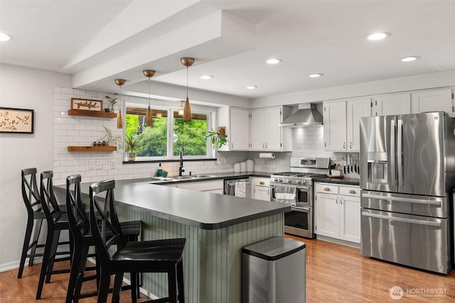 755 Elm St, Raymond, WA 98577 - kitchen with stainless steel appliances, wall chimney range hood, a peninsula, tasteful backsplash, and recessed lighting
