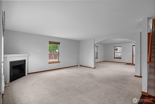 516 Emerald Ct SE, Rainier, WA 98576 - unfurnished living room with arched walkways, carpet flooring, a fireplace, and stairway