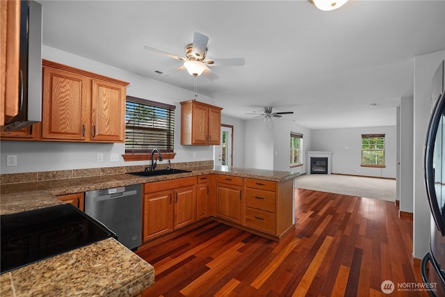 516 Emerald Ct SE, Rainier, WA 98576 - kitchen featuring stainless steel appliances, a peninsula, ceiling fan, dark wood-style flooring, and a glass covered fireplace