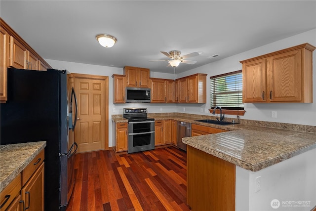 516 Emerald Ct SE, Rainier, WA 98576 - kitchen with stainless steel appliances, a peninsula, dark wood-style floors, a ceiling fan, and brown cabinetry