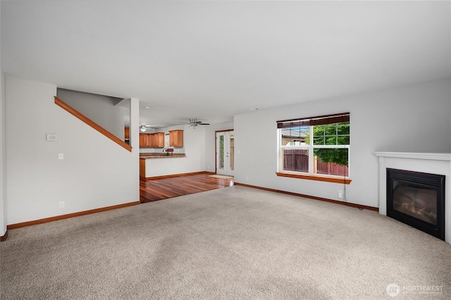 516 Emerald Ct SE, Rainier, WA 98576 - unfurnished living room with carpet, a glass covered fireplace, and a ceiling fan