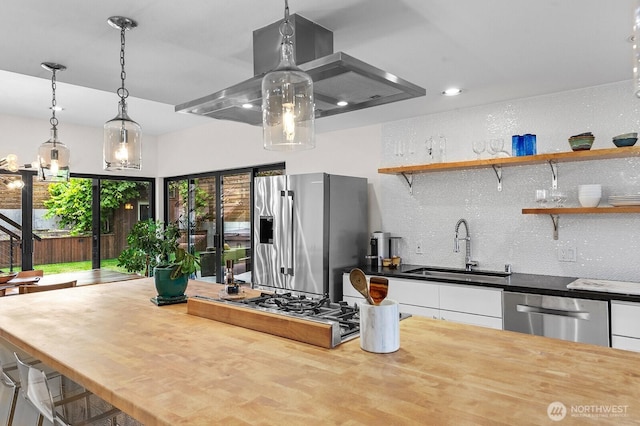 11017 Forest Ave S, Seattle, WA 98178 - kitchen featuring appliances with stainless steel finishes, ventilation hood, tasteful backsplash, white cabinetry, and hanging light fixtures