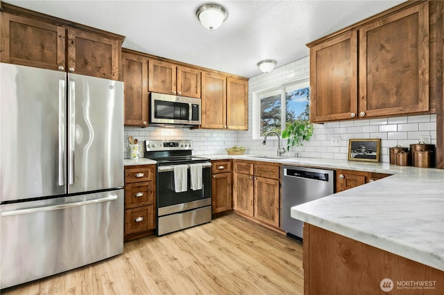 889 SW Kingma Ct, Oak Harbor, WA 98277 - kitchen with stainless steel appliances, light wood-style floors, light countertops, tasteful backsplash, and brown cabinets