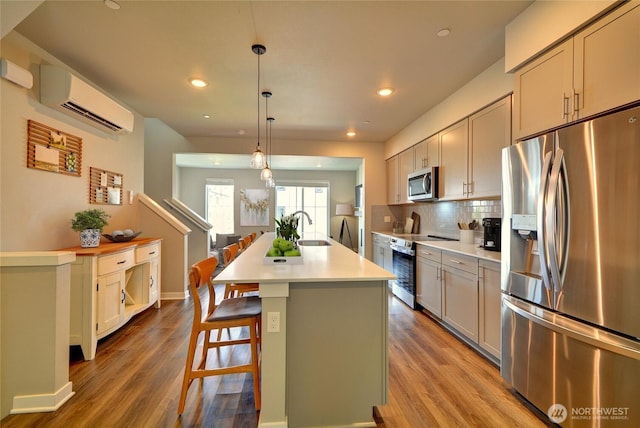 2014 101st Ave SE Unit 6, Lake Stevens, WA 98258 - kitchen featuring stainless steel appliances, a wall mounted air conditioner, wood finished floors, a kitchen island with sink, and tasteful backsplash
