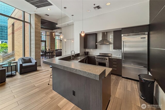 10650 NE 9th Pl Unit 3208, Bellevue, WA 98004 - kitchen with premium appliances, wall chimney range hood, light wood-style flooring, a breakfast bar area, and modern cabinets