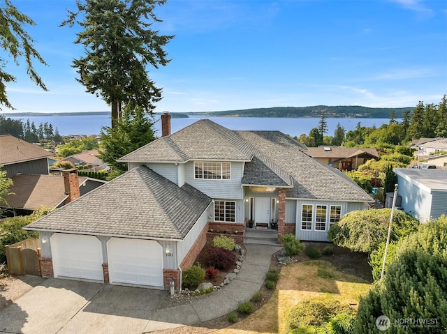 1021 N Sunset Dr, Camano Island, WA 98282 - traditional-style home with brick siding, an attached garage, a chimney, roof with shingles, and concrete driveway