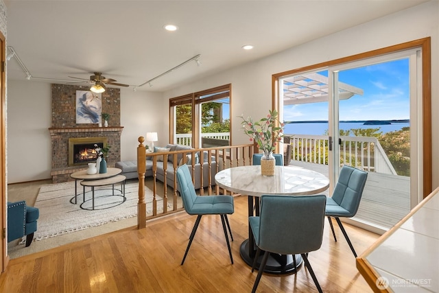 1021 N Sunset Dr, Camano Island, WA 98282 - dining area with rail lighting, a ceiling fan, wood finished floors, a brick fireplace, and recessed lighting