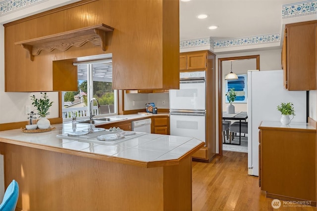 1021 N Sunset Dr, Camano Island, WA 98282 - kitchen featuring white appliances, a peninsula, light wood-style floors, brown cabinets, and tile counters