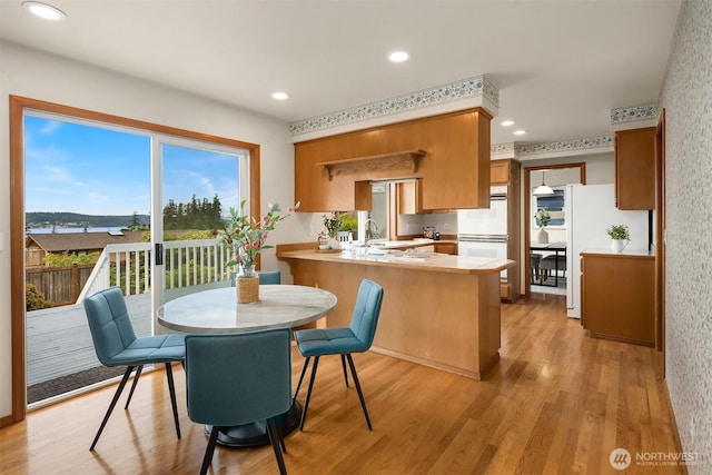 1021 N Sunset Dr, Camano Island, WA 98282 - kitchen featuring a peninsula, brown cabinetry, light countertops, light wood-style floors, and recessed lighting