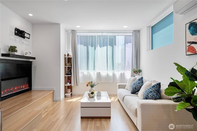 2620 NW 62nd St Unit B, Seattle, WA 98107 - living room featuring a wall unit AC, a glass covered fireplace, light wood-style floors, and recessed lighting