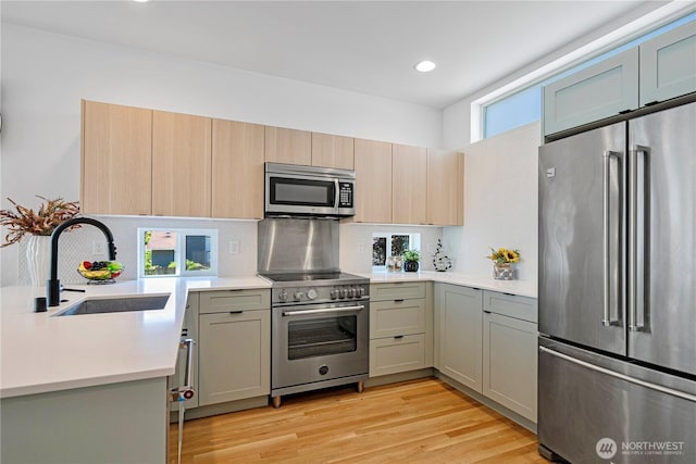 2620 NW 62nd St Unit B, Seattle, WA 98107 - kitchen featuring high end appliances, decorative backsplash, light countertops, light wood finished floors, and recessed lighting