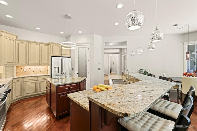 3303 Gravelly Beach Loop NW, Olympia, WA 98502 - kitchen with cream cabinetry, appliances with stainless steel finishes, a kitchen island with sink, dark wood-type flooring, and decorative backsplash