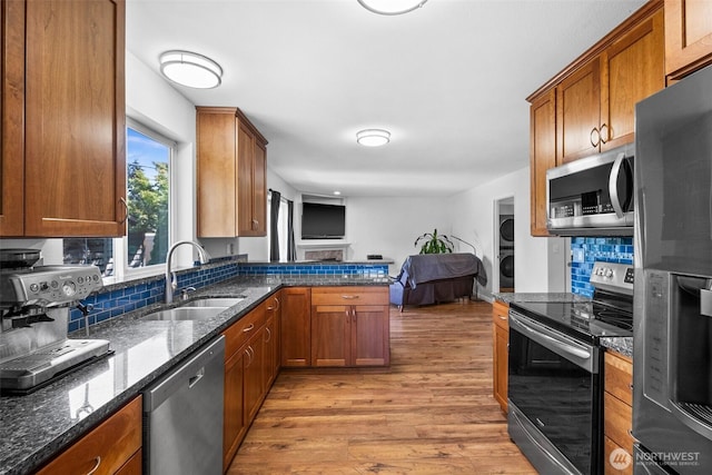 4509 224th Street Ct E, Spanaway, WA 98387 - kitchen featuring appliances with stainless steel finishes, stacked washing machine and dryer, open floor plan, light wood-type flooring, and tasteful backsplash
