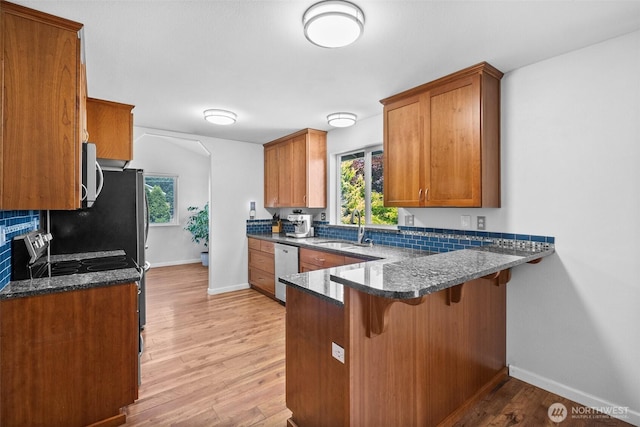 4509 224th Street Ct E, Spanaway, WA 98387 - kitchen featuring brown cabinets, a kitchen breakfast bar, light wood finished floors, a peninsula, and stainless steel electric range