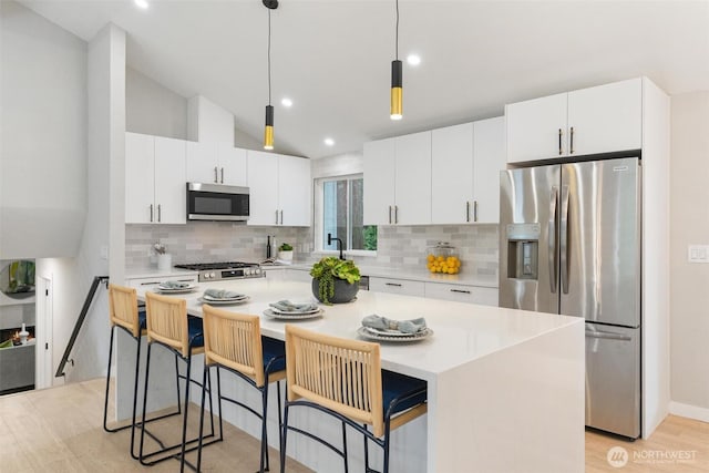 12804 NE 139th Ct, Kirkland, WA 98034 - kitchen featuring appliances with stainless steel finishes, light wood-style flooring, light countertops, a center island, and backsplash