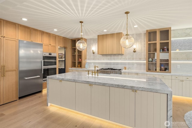 8411 202nd St SW, Edmonds, WA 98026 - kitchen with stainless steel appliances, light stone counters, an island with sink, light wood finished floors, and recessed lighting