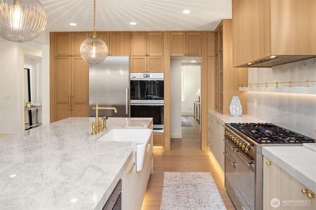 8411 202nd St SW, Edmonds, WA 98026 - kitchen with wall chimney range hood, high quality appliances, light wood finished floors, recessed lighting, and hanging light fixtures