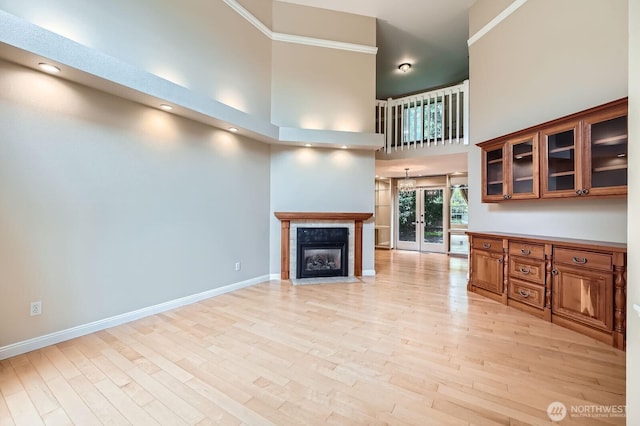 15831 Northup Way Unit 26, Bellevue, WA 98008 - unfurnished living room with light wood-style flooring, a towering ceiling, a tiled fireplace, and french doors