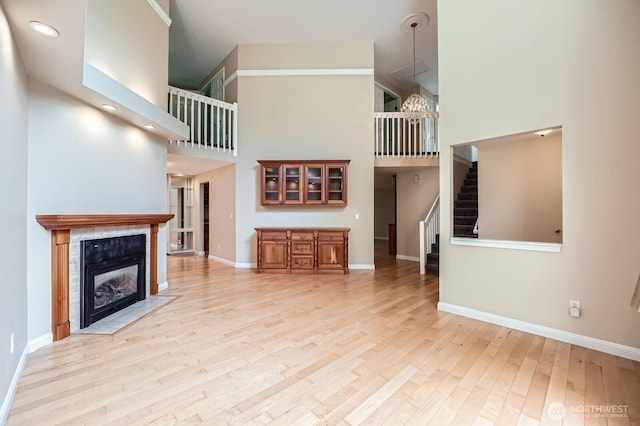 15831 Northup Way Unit 26, Bellevue, WA 98008 - unfurnished living room with a towering ceiling, stairs, light wood-type flooring, a tile fireplace, and recessed lighting